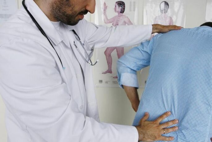 Arzt untersucht einen Patienten mit Rückenschmerzen im Lendenbereich